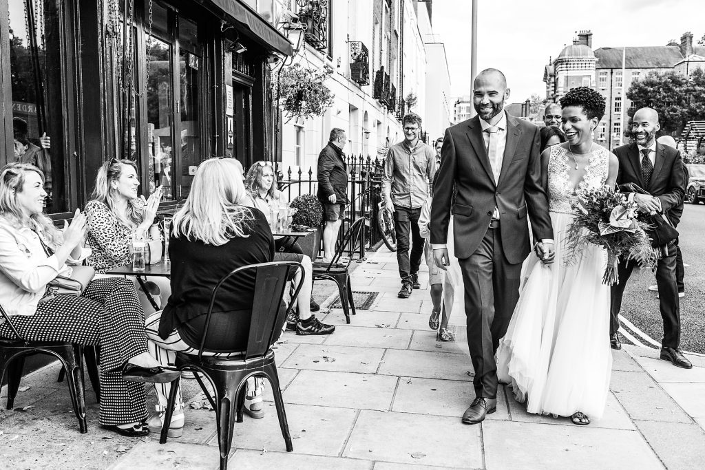 Wedding couple passing in front of a local pub in Chelsea after their ceremony at Chelsea Town Hall