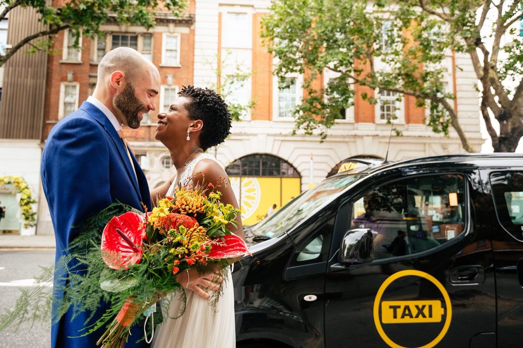 Bride meeting the groom in front of London Taxi at Chelsea Town Hall