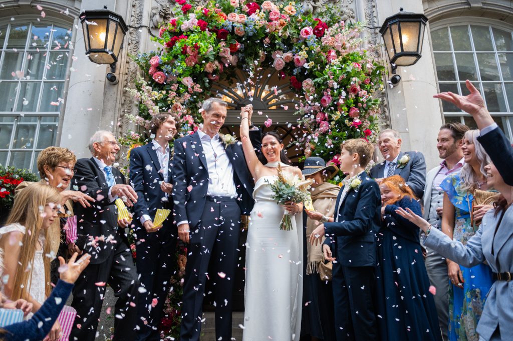 Couple coming out of Chelsea Town Hall with guests throwing confetti