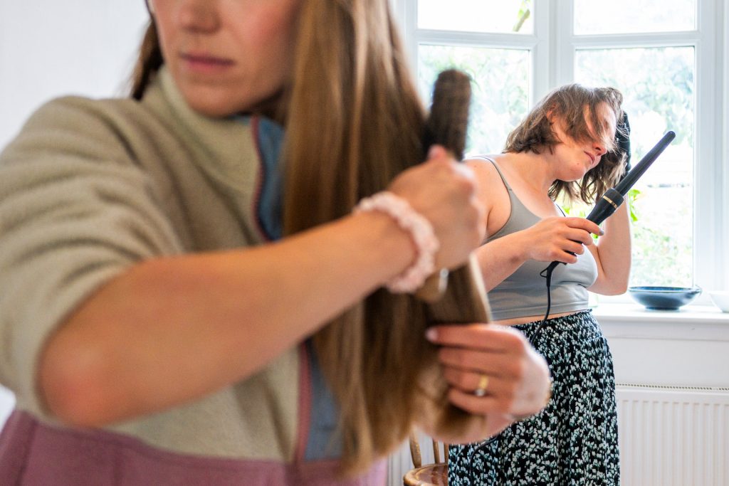 Bridesmaids curling their hair while getting ready for a wedding at The Lordship Pub, Dulwich