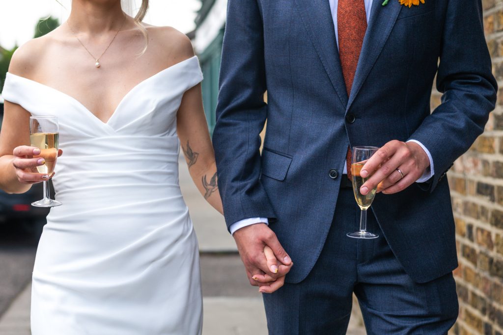 bride and groom with a Champagne drink while going to the Lordship Pub in Dulwich