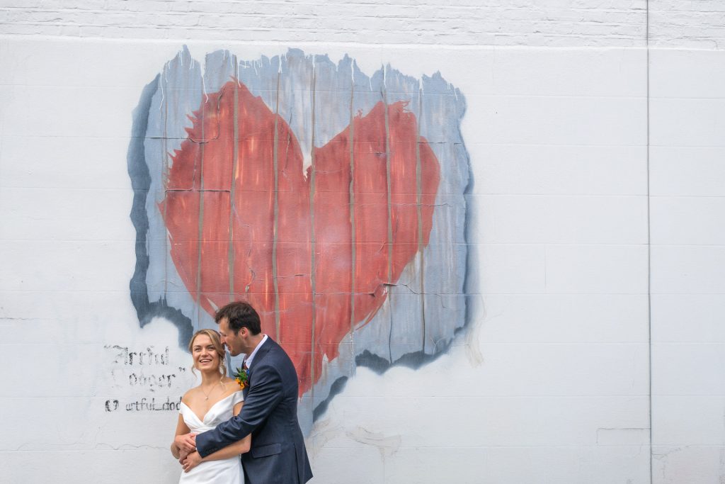 Bride and groom embracing in front of theheart mural near The Lordship Pub, Dulwich