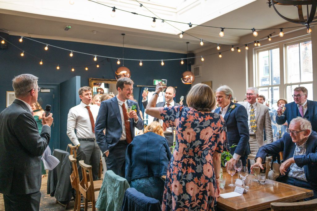 Guests raising a toast during speeches at The Lordship Pub reception, Dulwich