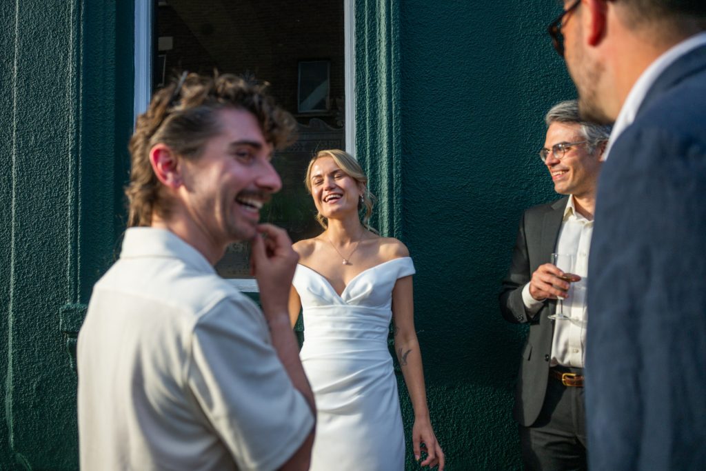 The bride laughing with guests in the evening sun outside The Lordship Pub, Dulwich