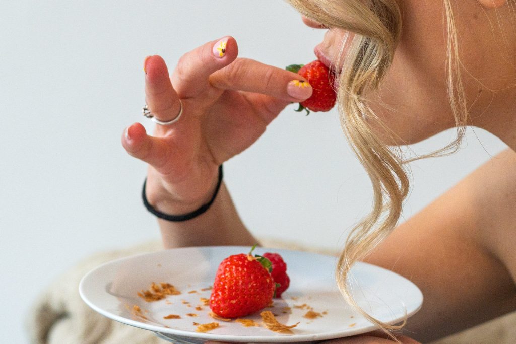 Bride enjoying a strawberry while getting ready for her wedding at The Lordship Pub, Dulwich, with delicate floral nail ar