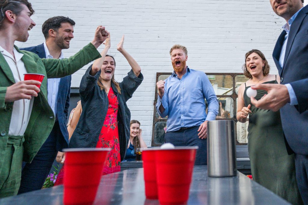 Wedding guests celebrating a beer pong win in the garden at The Lordship Pub, Dulwich
