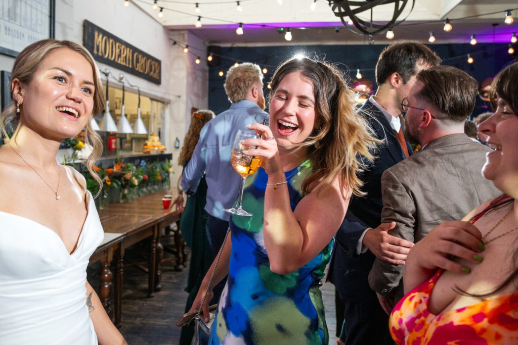 A guest laughing and dancing with an Aperol spritz at The Lordship Pub reception, Dulwich